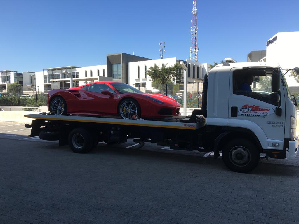 Autohaus flatbed tow truck carrying a red Ferrari sports car